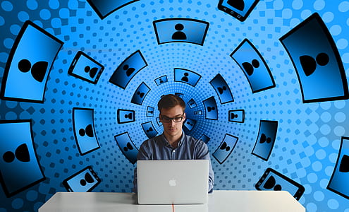 man sitting on table with blue background while using laptop thumbnail