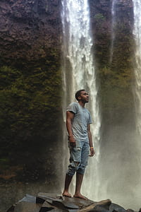 man standing near waterfalls thumbnail