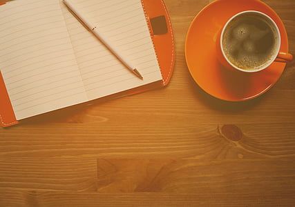 brown ceramic cup and saucer beside pen on table thumbnail