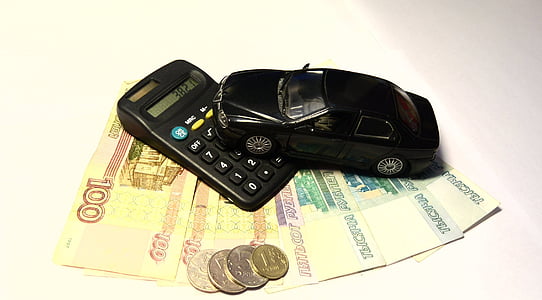 black die-cast metal sedan scale model on top of calculator and banknotes thumbnail