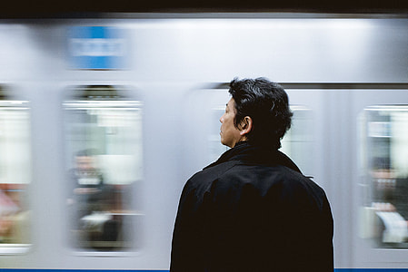 man in black jacket standing near train thumbnail