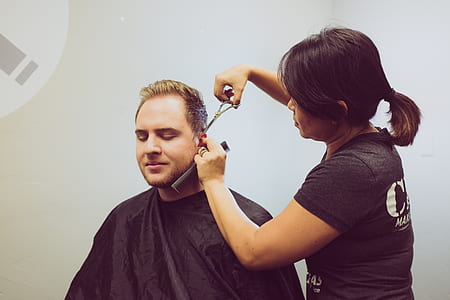 woman cutting hair of man under black apron thumbnail