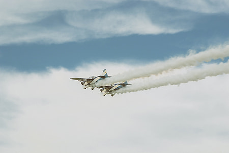 two white dog fighter planes throwing smoke on air under white cloudy skies thumbnail