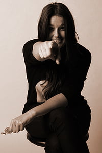 woman sitting on black stool while pointing with left index finger thumbnail