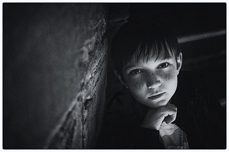 greyscale photo of boy learning on wall thumbnail