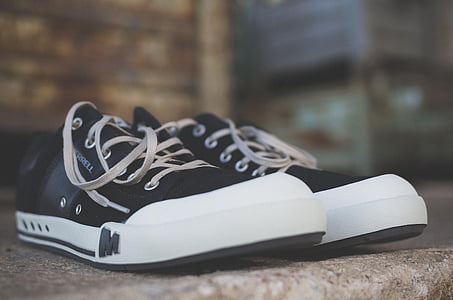 pair of black-and-white low-top sneakers on brown surface close-up photography thumbnail
