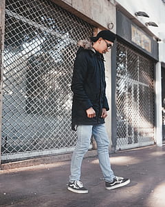side view of man standing beside chain-link fence thumbnail