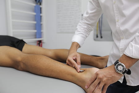 person in white dress shirt massaging ankle of person on bed thumbnail