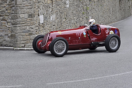 man riding red vintage racing car on road thumbnail