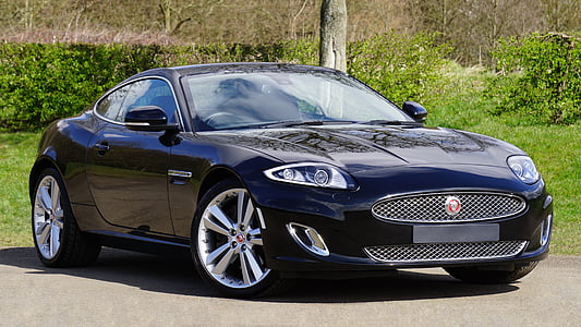 blue Jaguar XKR coupe parked near green grass field and pole thumbnail
