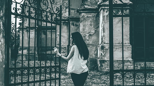 grayscale photo of woman holding metal gate thumbnail