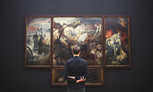 man in black dress shirt looking at paintings thumbnail