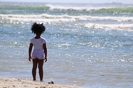 girl in white cap-sleeved shirt with gray denim short shorts outfit standing in front of sea during daytime thumbnail