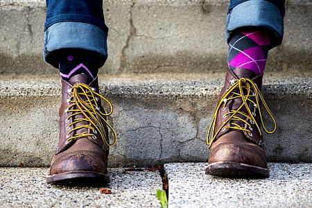 person wearing brown leather lace-up boots on gray concrete stair during daytime thumbnail