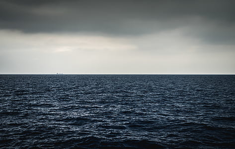 landscape photography of blue ocean under cloudy sky thumbnail
