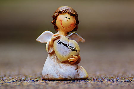 close-up photography of angel holding heart figurine thumbnail