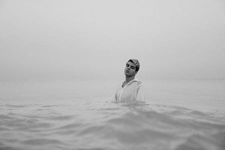 grayscale photo of man wearing dress shirt at the sea thumbnail
