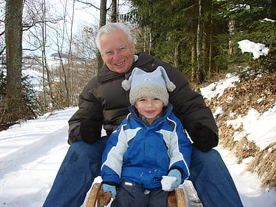 man and children riding on snow sled during daytime thumbnail