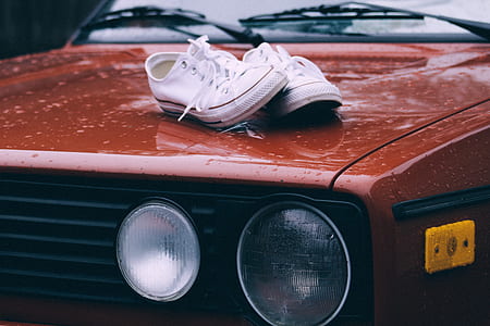 pair of white Converse All-Star low-tops on brown vehicle hood during daytime thumbnail