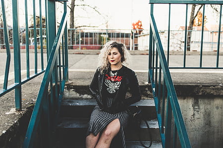 woman sitting on stair case while placing her both hands in jacket pocket thumbnail