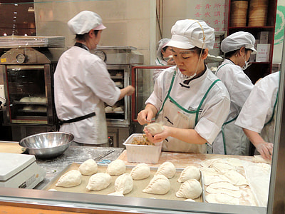 female pastry chef molding dough surrounded by cooking machines thumbnail