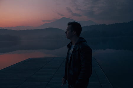 man standing on dock looking through during golden hour thumbnail