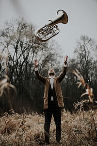 man standing on brown grass field throwing wind instrument on air thumbnail