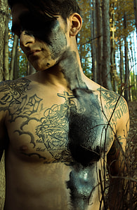 closeup photo of man with tattoos in the woods thumbnail