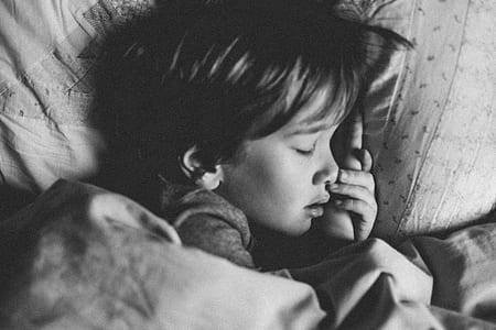 grayscale photography of boy sleeping on bed thumbnail