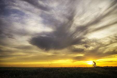 silhouette of person biking during sunset l thumbnail