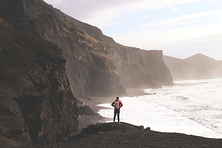 A hiker man stands on the dramatic coast of Iceland thumbnail
