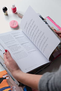 person reading book near nail lacquer bottle thumbnail