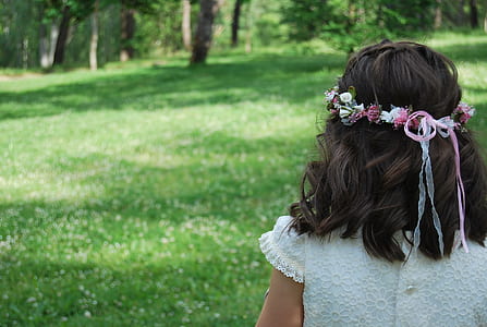 girl wearing white dress with pink headdress looking towards the trees during daytime thumbnail