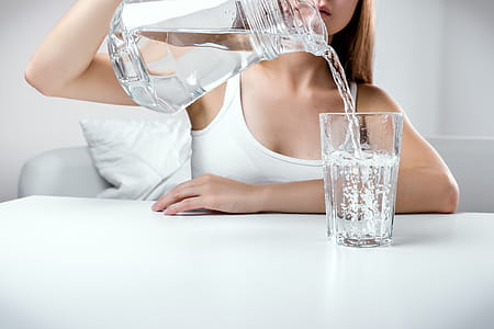 Close up of young girl pouring fresh pure water from pitcher into a glass thumbnail