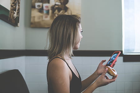 woman holding smartphone standing near white concrete wall thumbnail