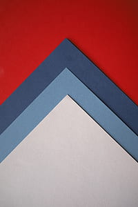 three white, blue, and black papers on red surface thumbnail
