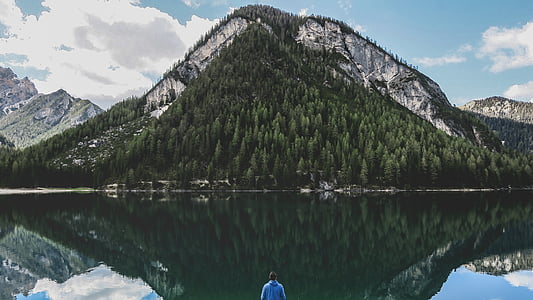 man standing near lake and mountain thumbnail