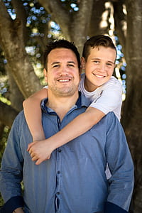 man wearing blue dress shirt carrying boy in his back thumbnail