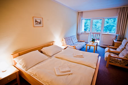 bed neatly folded bedspread beside sofa chairs thumbnail