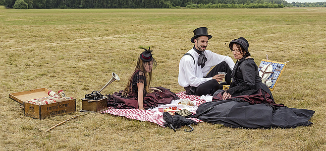 two women and man sitting on mat with basket and foods thumbnail