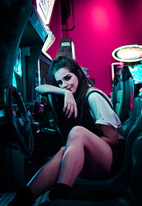 woman sitting on racing arcade machine thumbnail