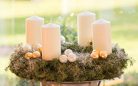 four white pillar candles on top of green wreath thumbnail