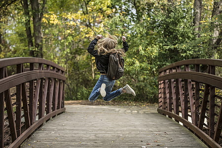 girl jump shot photo on brown wooden bridge thumbnail