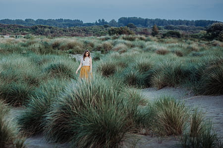 woman standing on green grass field during daytime thumbnail