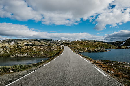 road near hill under white clouds thumbnail
