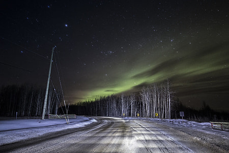 road near snow covered ground during nighttime thumbnail
