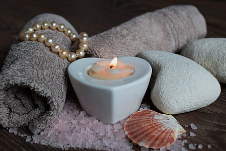 white candle beside sea shell and stone thumbnail
