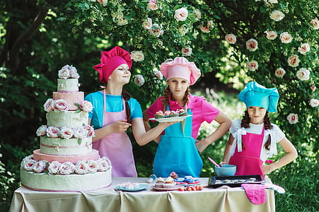 three girls baking cake near trees thumbnail
