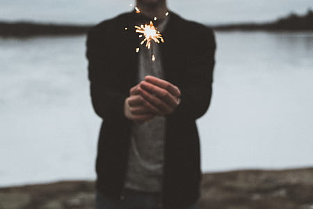 man holding firecracker near body of water thumbnail