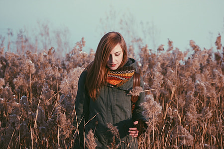 woman wearing black coat walking through a grassy field thumbnail